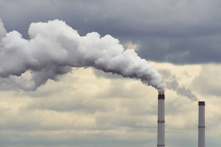 吸烟的发电厂的工业烟囱在黎明时用灰色的云污染空气.照片